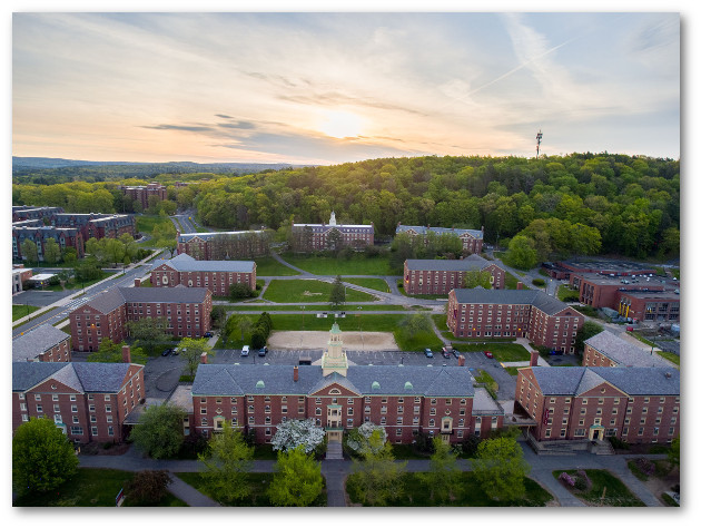 Northeast residence area at dusk.  Brick dormitories surround a central quad and a wooded hill is in the background. The East residence area can be partially seen on the left.