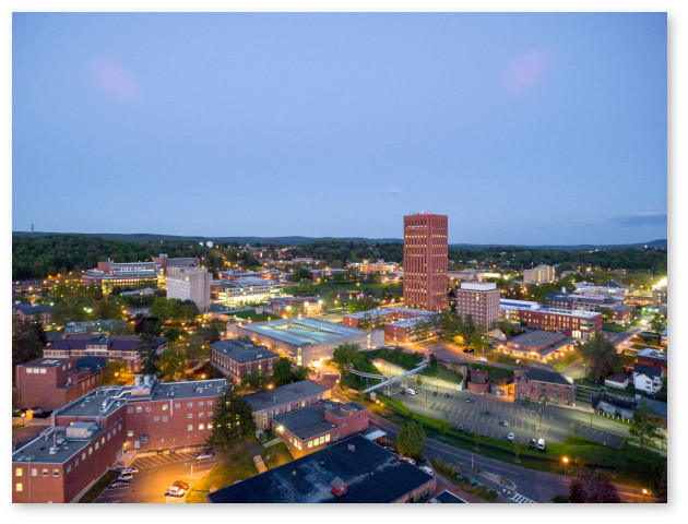 Aerial view of campus at dusk. Building lights glow in the darkening sky.