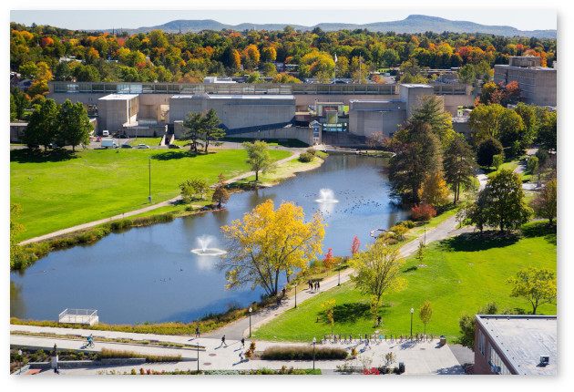 Aerial view of campus looking south from a high floor in the library. The pond with two fountains and the Fine Arts Center are prominent, and the Holyoke range is visble in the background.